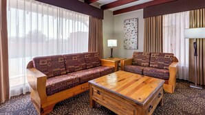 A cozy living room with a wooden sofa and armchair, a wooden coffee table, and a patterned rug.