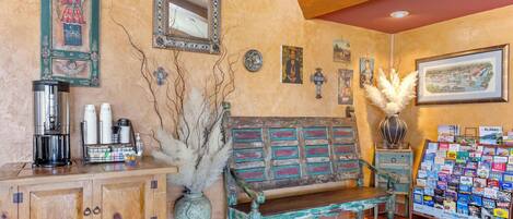 A cozy lobby with a wooden bench, a coffee station, a bulletin board, and decorative wall art.