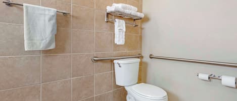 Et badeværelse med toilet, håndklædestige, hylde med håndklæder og toiletpapirholder.