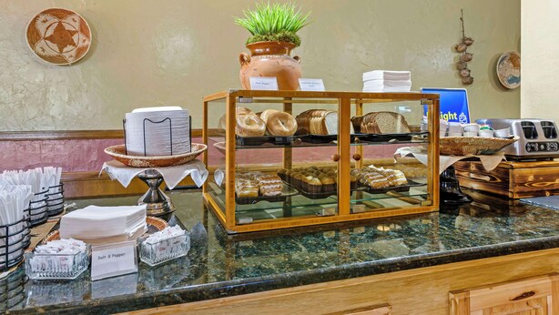 A buffet area with a variety of baked goods, a coffee station, and a decorative plant.