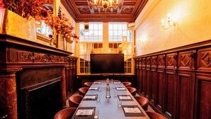 A conference room with a long table, chairs, a fireplace, and a large screen.