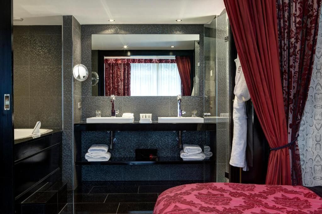 A modern bathroom with a large mirror, two sinks, and a vanity with towels.