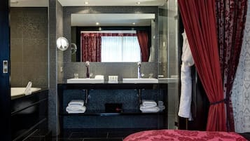 A modern bathroom with a large mirror, two sinks, and a vanity with towels.