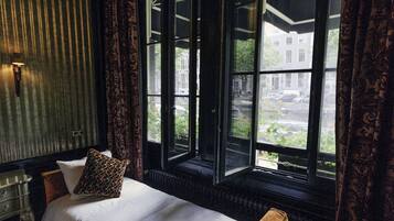Un dormitorio con una cama grande, una ventana con cortinas y un radiador.
