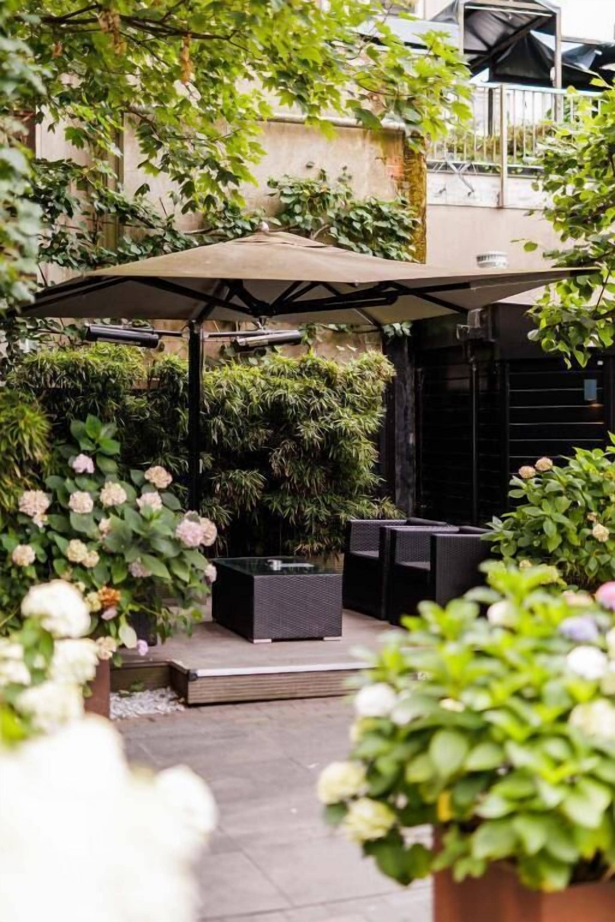An outdoor seating area with a covered patio, surrounded by lush greenery and potted plants.