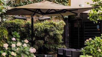 An outdoor seating area with a covered patio, surrounded by lush greenery and potted plants.
