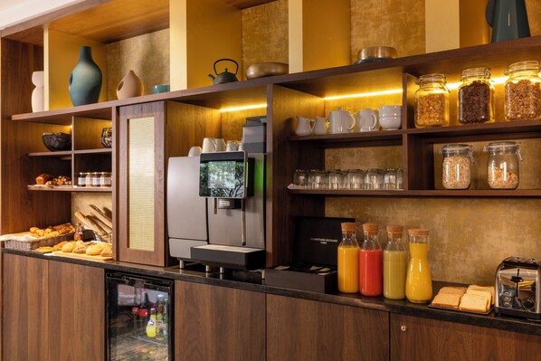 A breakfast bar with a coffee machine, a refrigerator, and various food items. - Hotel Etoile Maillot (Paris)