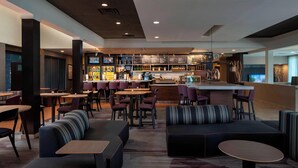 A modern bar area with seating arrangements, a counter, and a variety of beverages on display. - Courtyard by Marriott Nashville Brentwood (Brentwood)