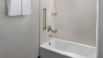 Une salle de bain moderne avec une baignoire blanche, un porte-serviettes avec deux serviettes et une cabine de douche en verre.