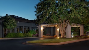 A modern hotel entrance with a covered walkway, large trees, and well-maintained landscaping. - Courtyard by Marriott Nashville Brentwood (Brentwood)