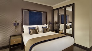 A hotel room with a large bed, a mirror, a nightstand, and a wall with a textured pattern.
