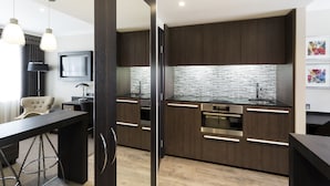 A modern kitchen with dark wood cabinets, stainless steel appliances, and a tiled backsplash.