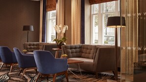 A modern living room with a sectional sofa, two armchairs, a small wooden side table, and a floor lamp.
