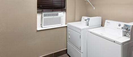 A laundry room with a wall-mounted dryer, a stacked washer and dryer, and a window with blinds.