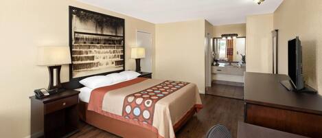Una habitación de hotel con cama, mesitas de noche, escritorio, televisor y baño a la vista.