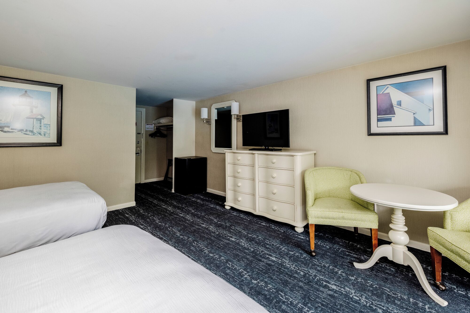 A hotel room with a bed, a desk, a chair, a dresser, and a television.