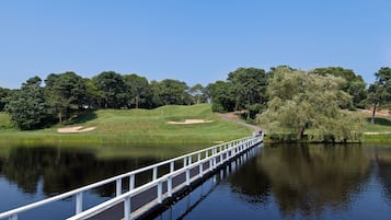 A bridge over a calm lake with a golf course in the background.