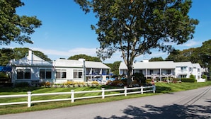 A row of white, two-story buildings with a white fence in front, likely a motel or small hotel.
