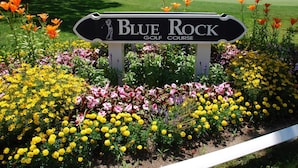 A sign for Blue Rock Golf Course surrounded by a variety of colorful flowers.