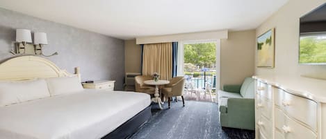 A hotel room with a large bed, a desk, a chair, a dresser, and a view of the outdoors.