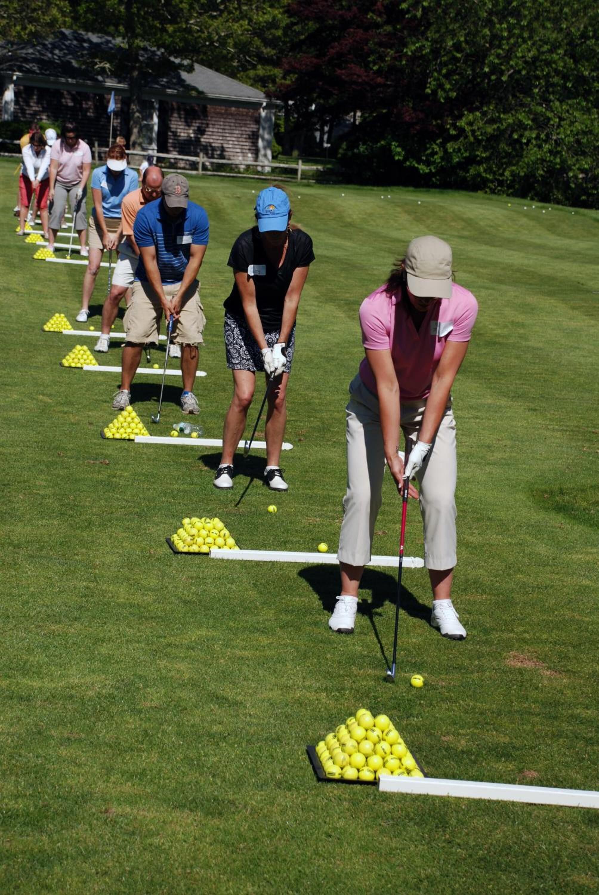 A group of people on a golf course, each preparing to putt a golf ball.