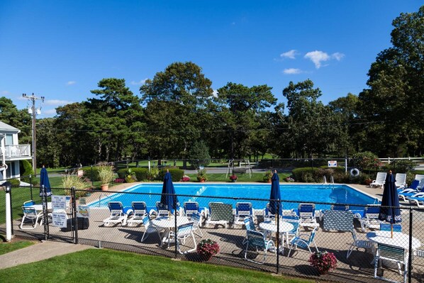 Una piscina al aire libre de temporada, sombrillas