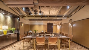Une salle de conférence avec une longue table, des chaises, un plafond décoratif et une horloge fixée au mur.