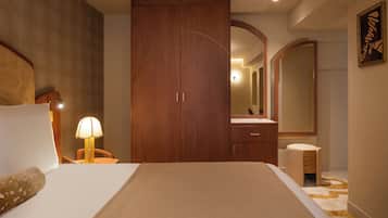 Quarto com cama grande, armário de madeira, escrivaninha com abajur e espelho.