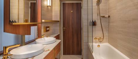 A modern bathroom with two sinks, a large mirror, and a bathtub.