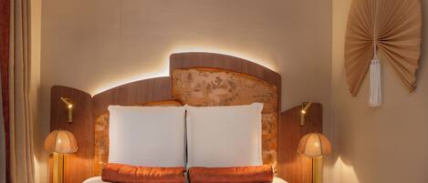 A hotel room with a large bed, two bedside lamps, a wall-mounted fan, and a wooden headboard.