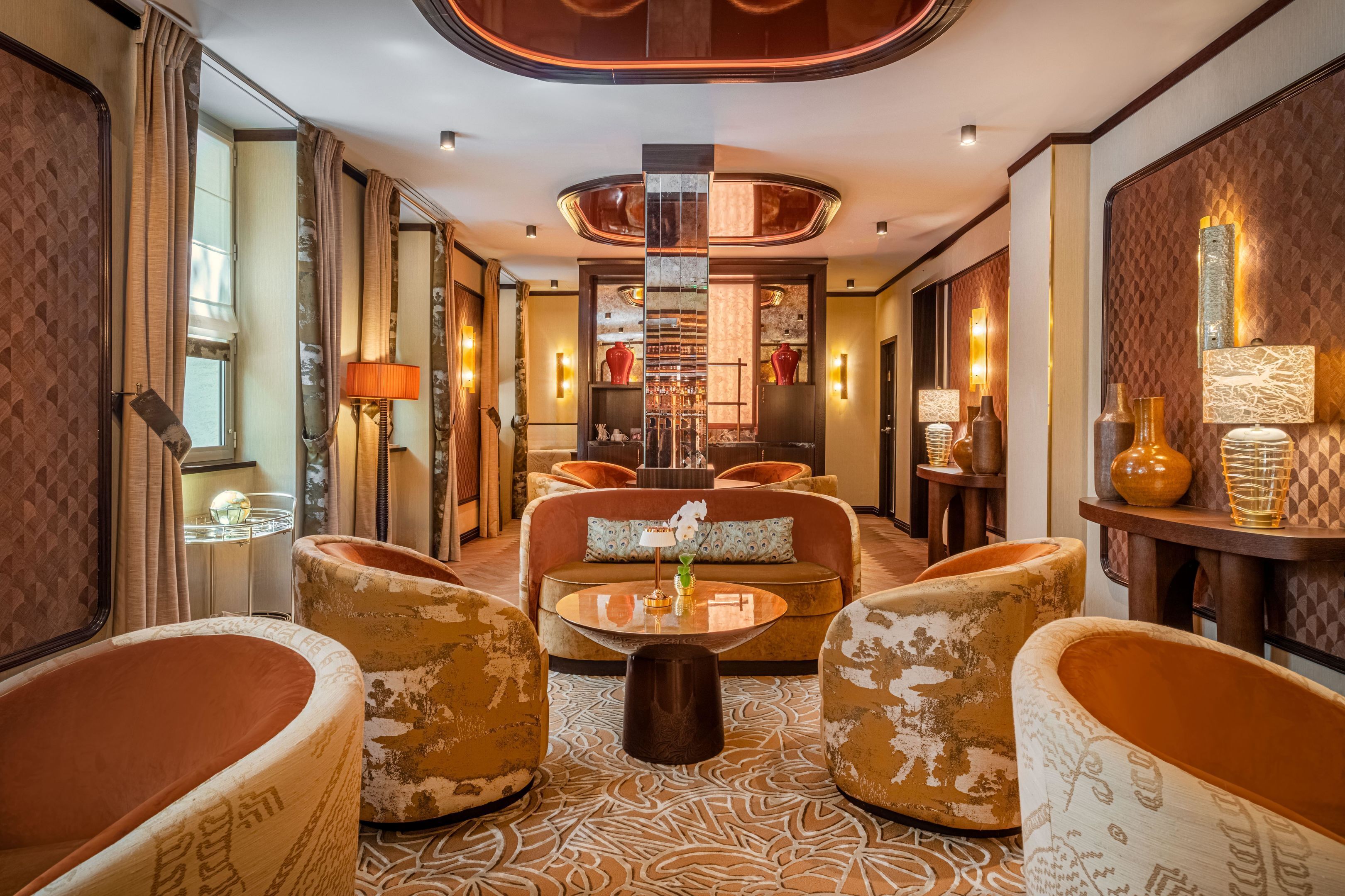 A hotel lobby with a central seating area, a bar, and a decorative wall.