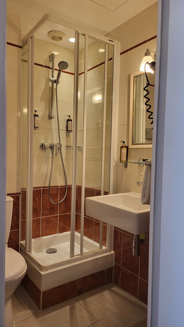 A modern bathroom with a glass-enclosed shower, a white sink, and a toilet. - Hotel Magda Champs Elys ées (Paris)