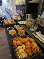 A buffet with various food items including bread, pastries, and condiments.
