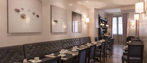 A restaurant with a long counter, cushioned seating, and wall-mounted artwork.