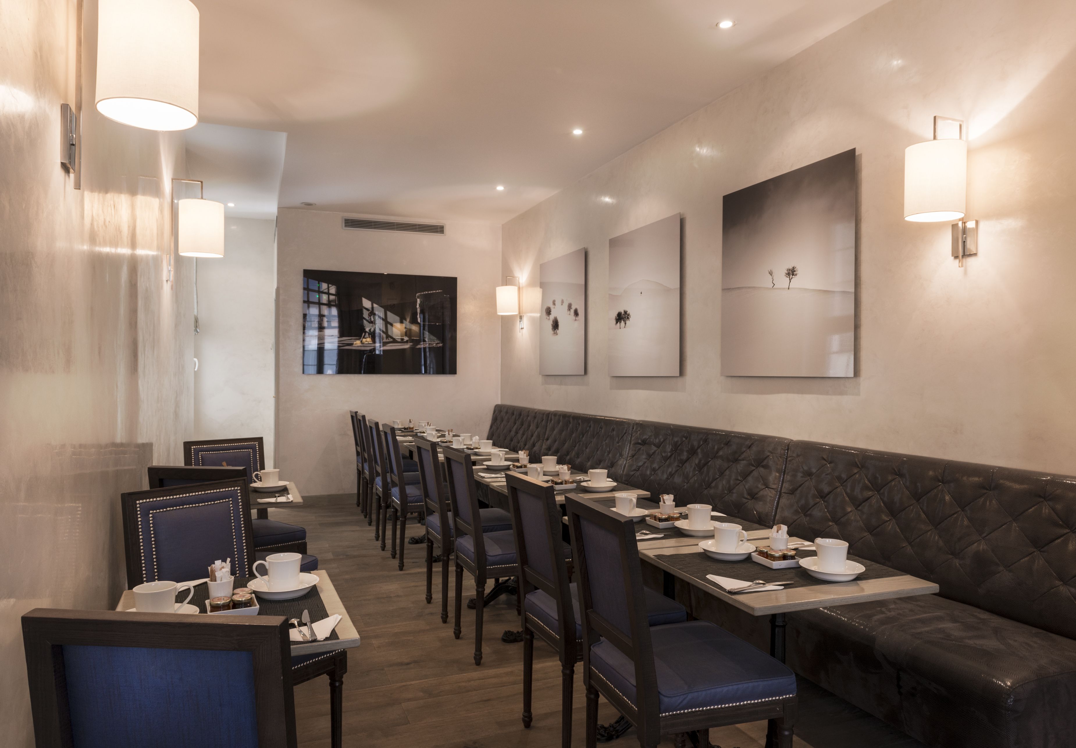 A restaurant with a long counter, cushioned seating, and wall-mounted light fixtures.