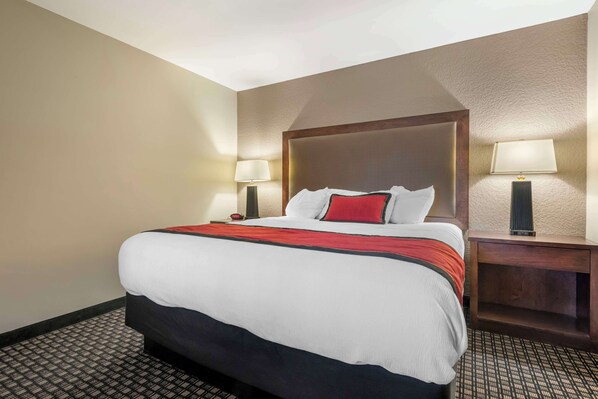 A hotel room with a large bed, two bedside lamps, and a nightstand.