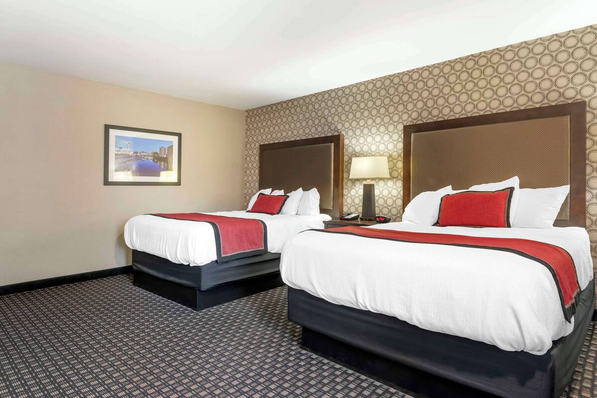 Ein Hotelzimmer mit zwei Betten, einem gerahmten Bild an der Wand und einem gemusterten Teppich.