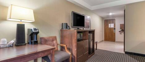 A hotel room with a wooden desk, a television, a coffee maker, and a microwave.