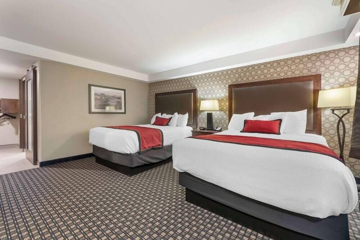 Ein Hotelzimmer mit zwei Betten, einem gemusterten Teppich und einem gerahmten Bild an der Wand.