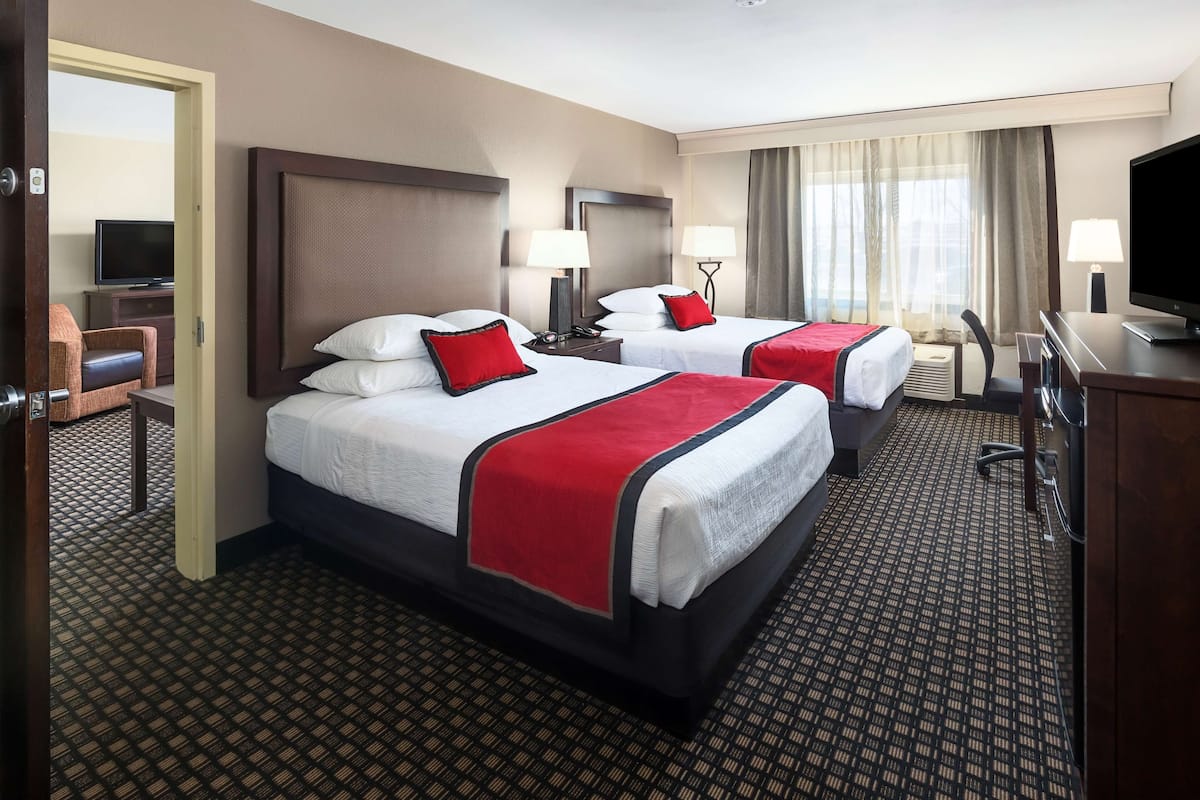 Ein Hotelzimmer mit zwei Betten, einem Fernseher, einem Schreibtisch und einem Stuhl.