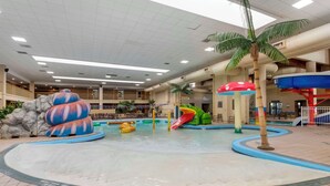 An indoor water park with a central pool, slides, and various play structures.