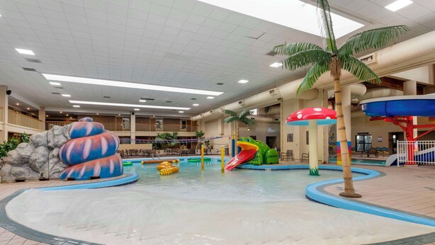 Parque acuático interior con piscina central, toboganes y diversas estructuras de juego.