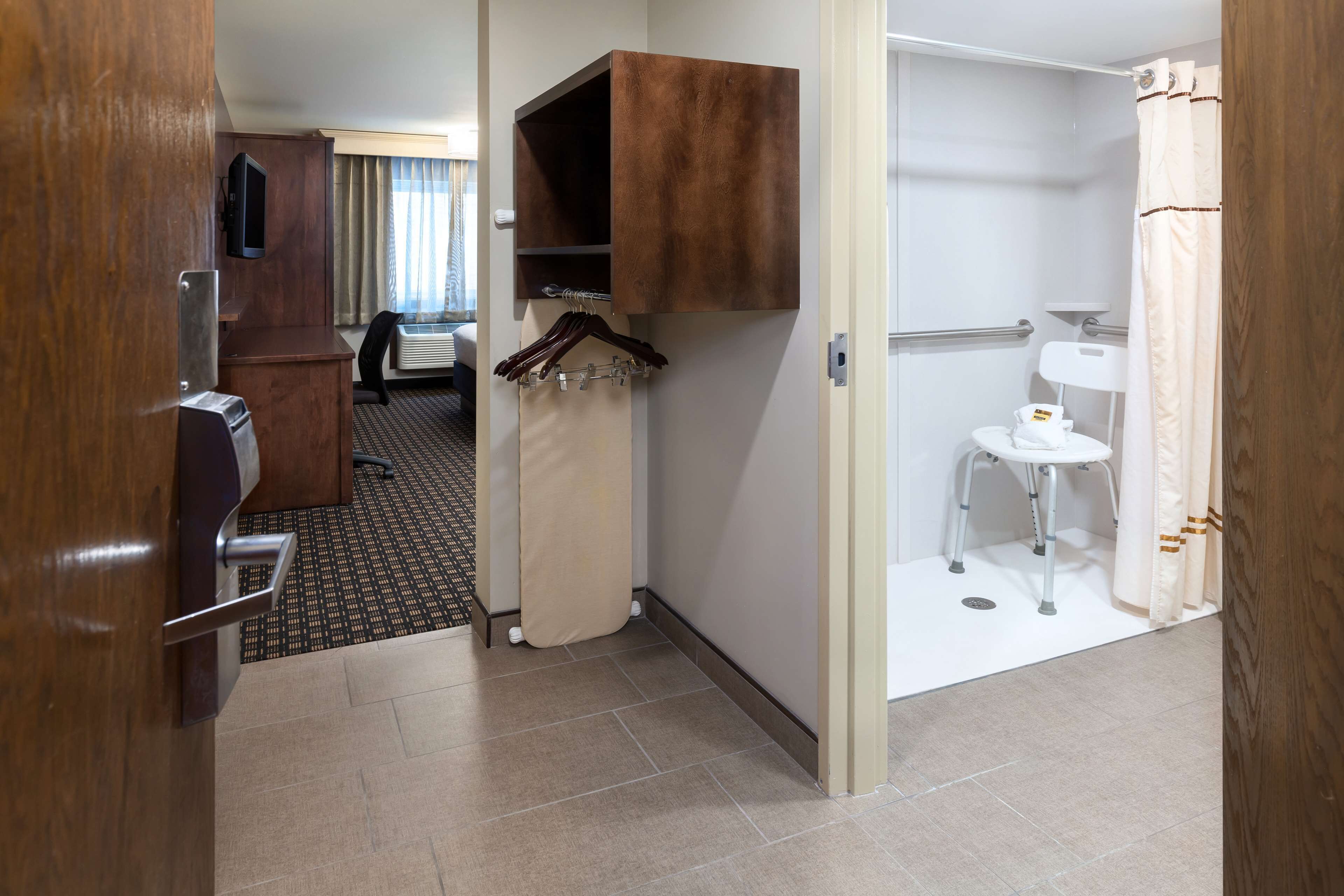 Et hotelværelse med et træskab, et lille hvidt toilet og et bruseområde.