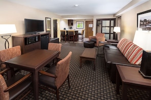 A hotel room with a dining area, a sofa, a TV, and a kitchen area. - Best Western Plus Ramkota Hotel (Sioux Falls)