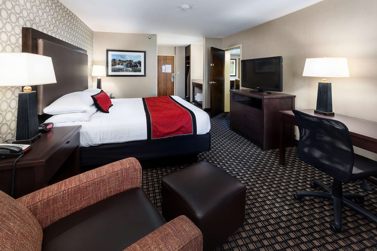 Ein Hotelzimmer mit Bett, Schreibtisch, Stuhl, Fernseher und Lampe.