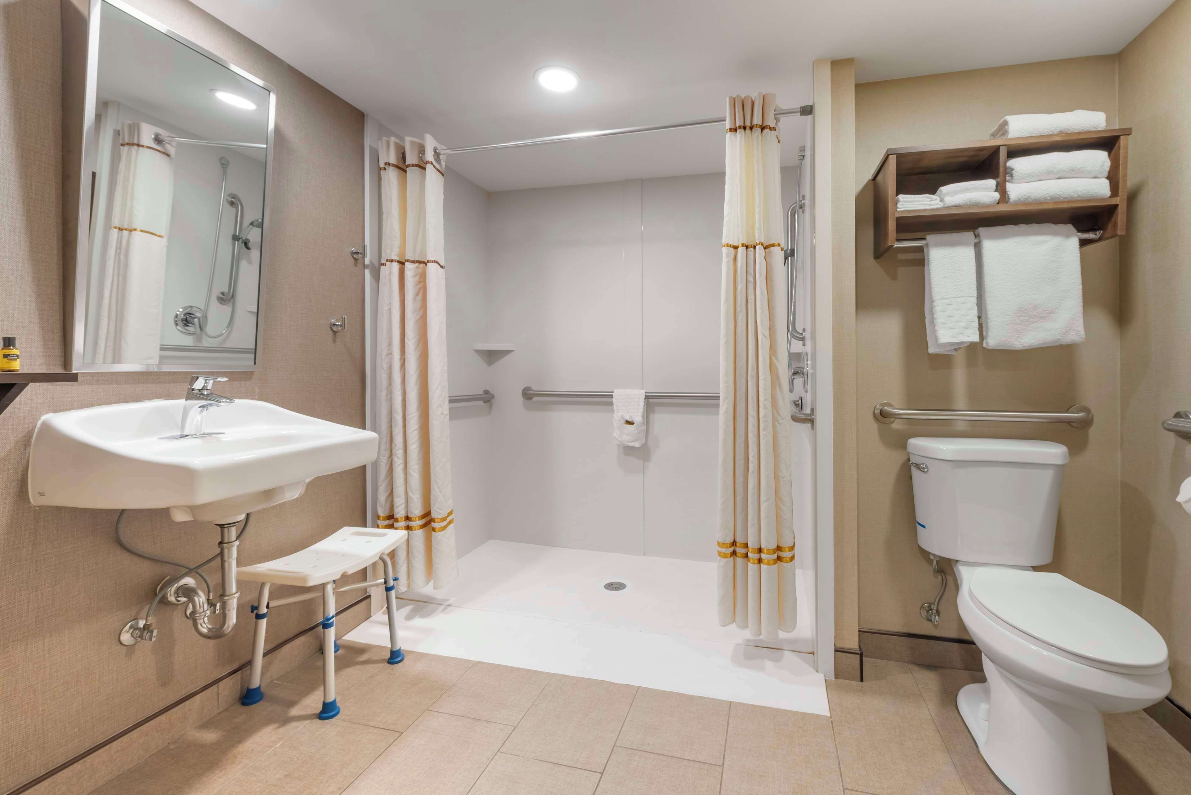 A modern bathroom with a sink, toilet, shower, and a step for accessibility.