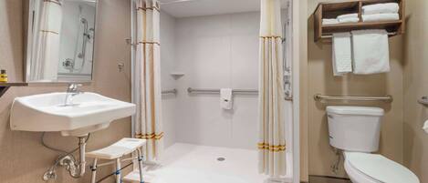 A modern bathroom with a sink, toilet, shower, and a step for accessibility.