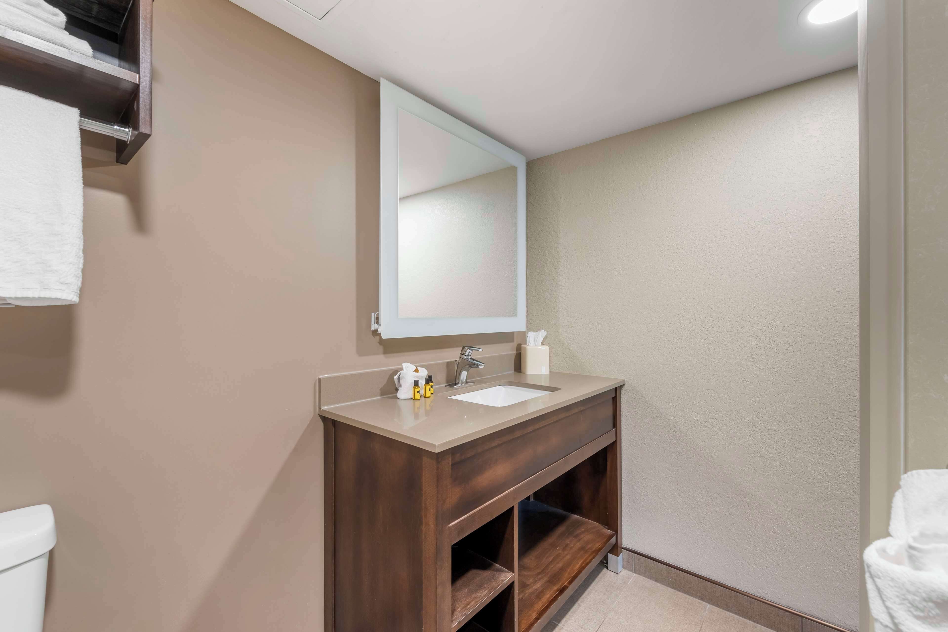 Une salle de bain avec un meuble-lavabo en bois foncé, un lavabo blanc et un miroir au-dessus.