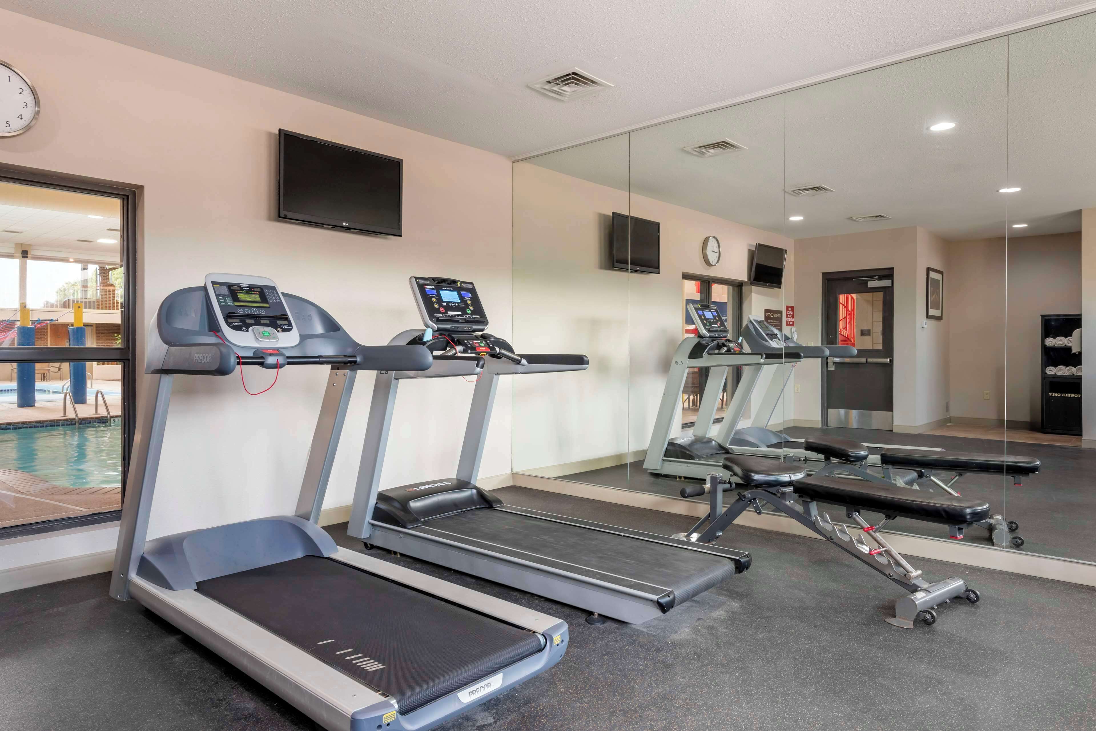 A gym with treadmills, a weight bench, and a wall-mounted TV.
