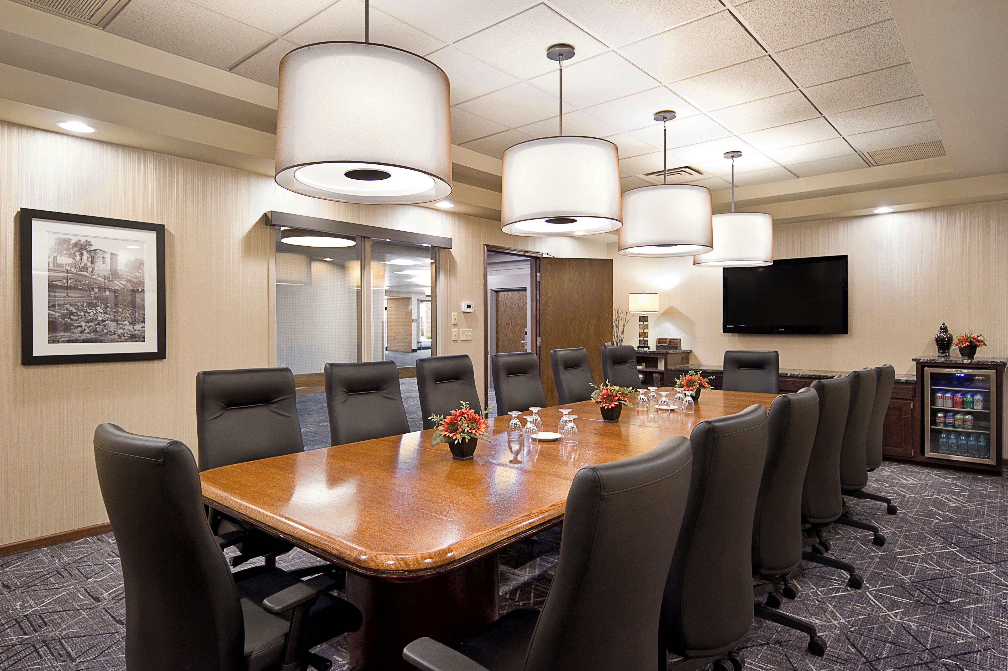 A conference room with a long table, multiple chairs, and overhead lighting.